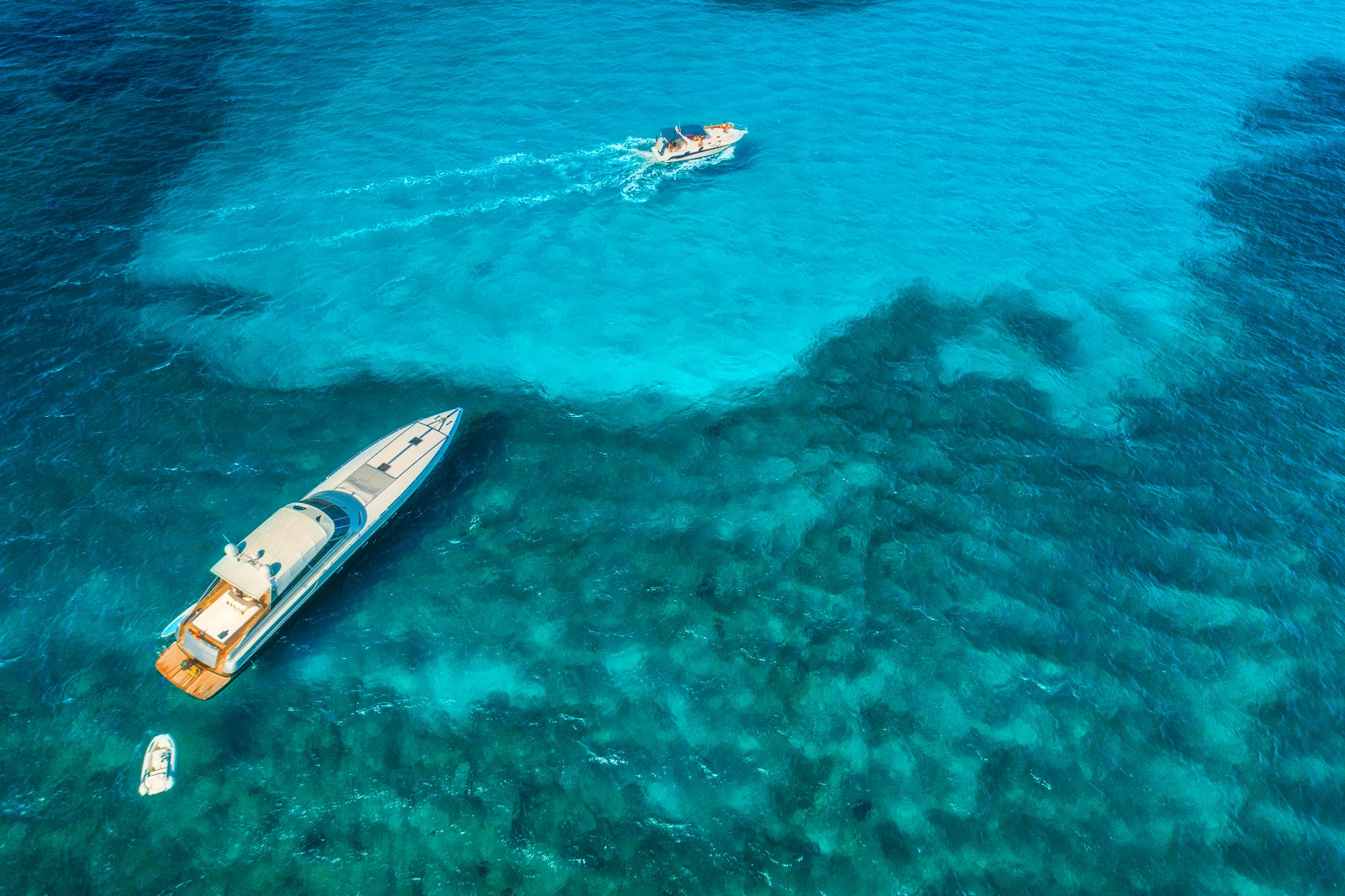 Exclusive Yachts - Yachts at the sea in Balearic islands, Spain. Aerial view of luxury floating boat in transparent blue water at sunny day. Summer landscape. Top view from drone. Seascape with motorboat in bay. Travel