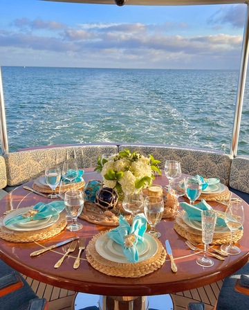 Aft Deck of Motor Yacht Star Sapphire Exclusive Yachts - Aft deck of a yacht set for an upscale meal, with turquoise-themed tableware against the ocean horizon.