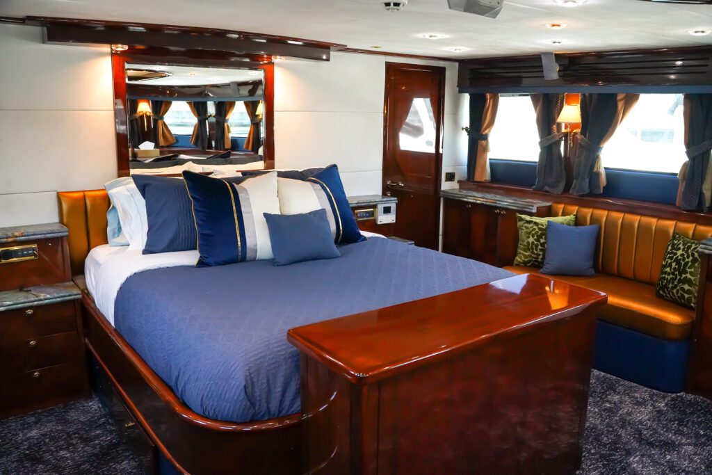 Exclusive Yachts - The stateroom aboard the MY Star Sapphire features a polished wooden finish, navy accents, and plush leather seating, embodying nautical elegance. Bed