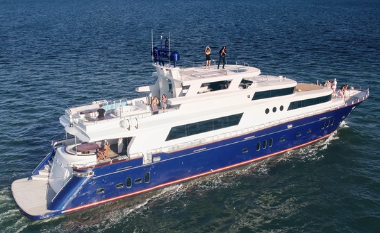 Exclusive Yachts - A blue and white yacht sails on tranquil waters under clear skies, with guests lounging and enjoying the serene environment. Motor Yacht Star Sapphire