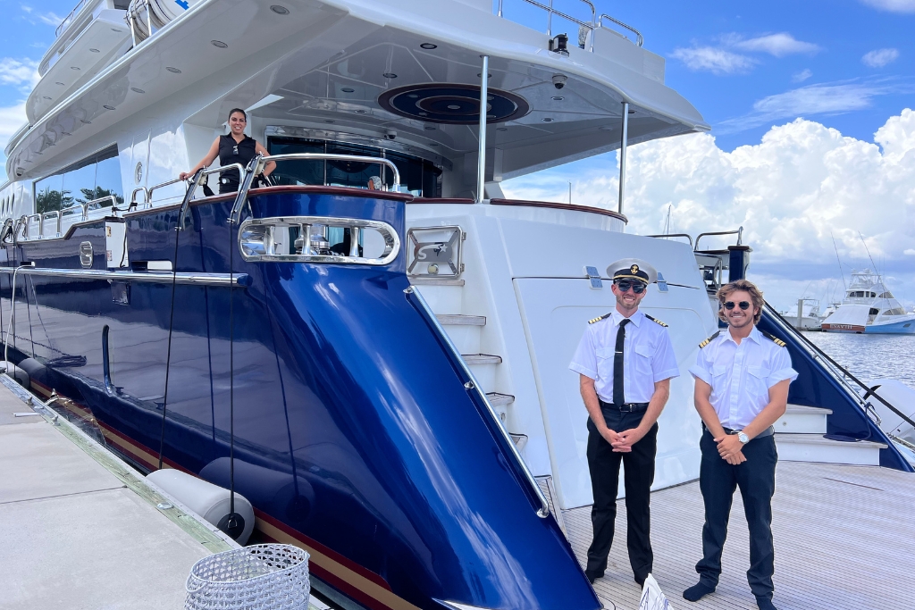 Crew posing in front of M/Y Star Sapphire Exclusive Yachts - Crew members pose confidently aboard the MY Star Sapphire, showcasing the yacht's impressive blue hull and white superstructure.